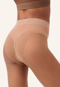 Slip beige senza cuciture con una superficie liscia e un elastico in vita. Il design presenta un taglio a vita media e dettagli di cucitura discreti.