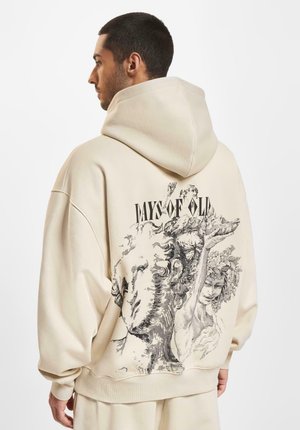 Beige oversized hoodie featuring a graphic print on the back depicting classical figures, with the text "DAYS OF OLD" prominently displayed.