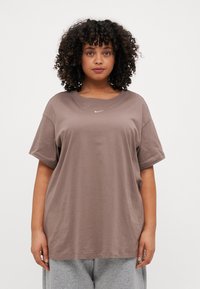 Rudas per didelis medvilnės T-shirt, su trumpomis rankovėmis ir apvaliu kaklu. Mažas baltas Nike logotipas yra įsikūręs centre ant krūtinės.