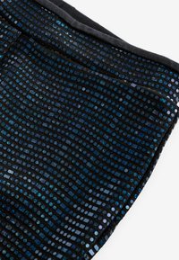 Zwarte stof met een scala aan glinsterende blauwe en zilveren pailletten, gerangschikt in een golvend patroon, met een gladde zwarte rand langs de rand.