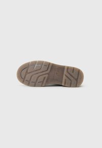 Semelle en caoutchouc avec une surface texturée et motif ; couleur beige avec une nuance de brun clair ; plusieurs rainures pour une meilleure adhérence et traction.