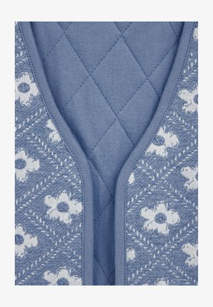 Modrý prešívaný materiál so kvetinovým vzorom. Dizajn má hladkú štruktúru s kontrastným pevným modrým lemovaním okolo výstrihu.