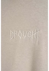 Jasno beżowy sweter z teksturowanym, nieregularnym białym haftem słowa "DROUGHT" na przedzie.