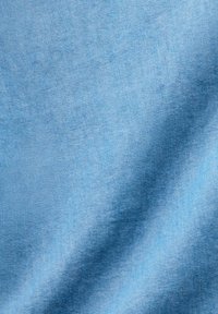 Tissu bleu clair avec une surface lisse et légèrement texturée, affichant des variations subtiles de couleur et d'ombrage. Convient pour les vêtements ou le rembourrage.