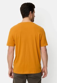 Kurzärmeliges T-Shirt mit Rundhalsausschnitt in kräftigem Orange, gefertigt aus weichem Stoff. Es zeichnet sich durch eine lockere Passform und einen geraden Saum aus.