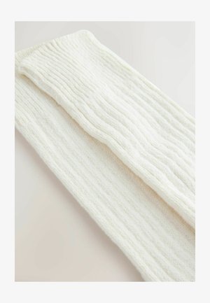 Off-white pleten šal z rebrasto teksturo, mehkega materiala in pravokotne oblike, nežno zložen, da pokaže dve plasti.