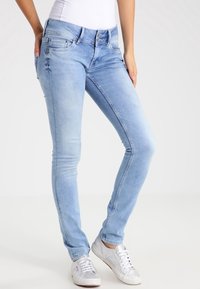 Ljusblå skinny jeans i denim med subtila blekningar, fem fickor och en klassisk knapp- och dragkedjestängning. Matchas med vita sneakers.