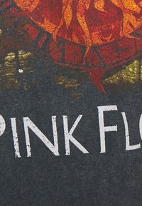 Mörkgrå t-shirt med en färgglad grafik av en låga och klockdesign, med "PINK FLOYD" i sliten vit text.