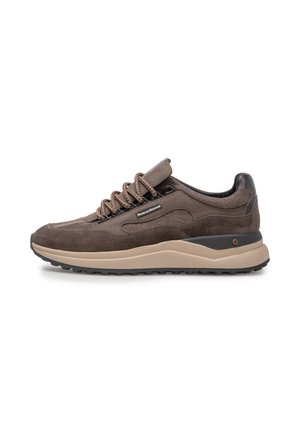 Bruine suède en leren sneaker met beige zool, met patroon gesneden veters en een zijlogo op een witte achtergrond, gezien van de buitenkant.