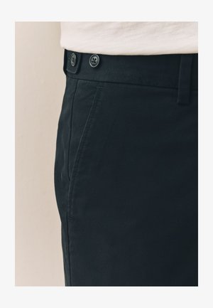 Pantalon en coton noir à texture lisse, doté de deux boutons noirs à la taille et de poches latérales pour plus de praticité.