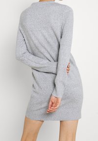 Grå stickad klänning med långa ärmar, rund halsringning och ribbade muddar. Tyget verkar mjukt och lätt strukturerat.