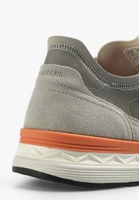 Hellgraue Sneaker mit Wildleder- und Mesh-Oberflächen, ausgestattet mit einer orangefarbenen Schaum-Zwischensohle und einer weißen Gummisohle. Dezentes Branding an der Ferse.