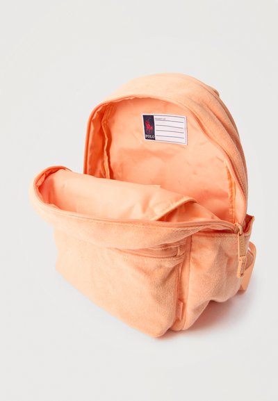 Αντικείμενο από πετσέτα τερρυ σε ροδακινί χρώμα, με το κύριο διαμέρισμα ανοιχτό, που δείχνει την εσωτερική επένδυση σαν σατέν και μια ετικέτα με την επωνυμία Polo στο εσωτερικό.