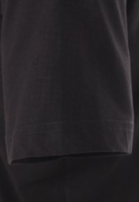 Czarna bawełniana koszulka z krótkim rękawem i czystym, przyszytym wykończeniem; gładka faktura, brak widocznych wzorów lub akcentów.