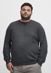Pulover gri închis cu mâneci lungi, dintr-un material texturat, cu decolteu rotund. Prezintă detalii tricotate contrastante la guler.