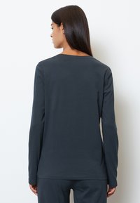 Maglia a maniche lunghe di un grigio scuro realizzata in tessuto morbido. Presenta un collo rotondo e una vestibilità rilassata, vista da dietro senza decorazioni.