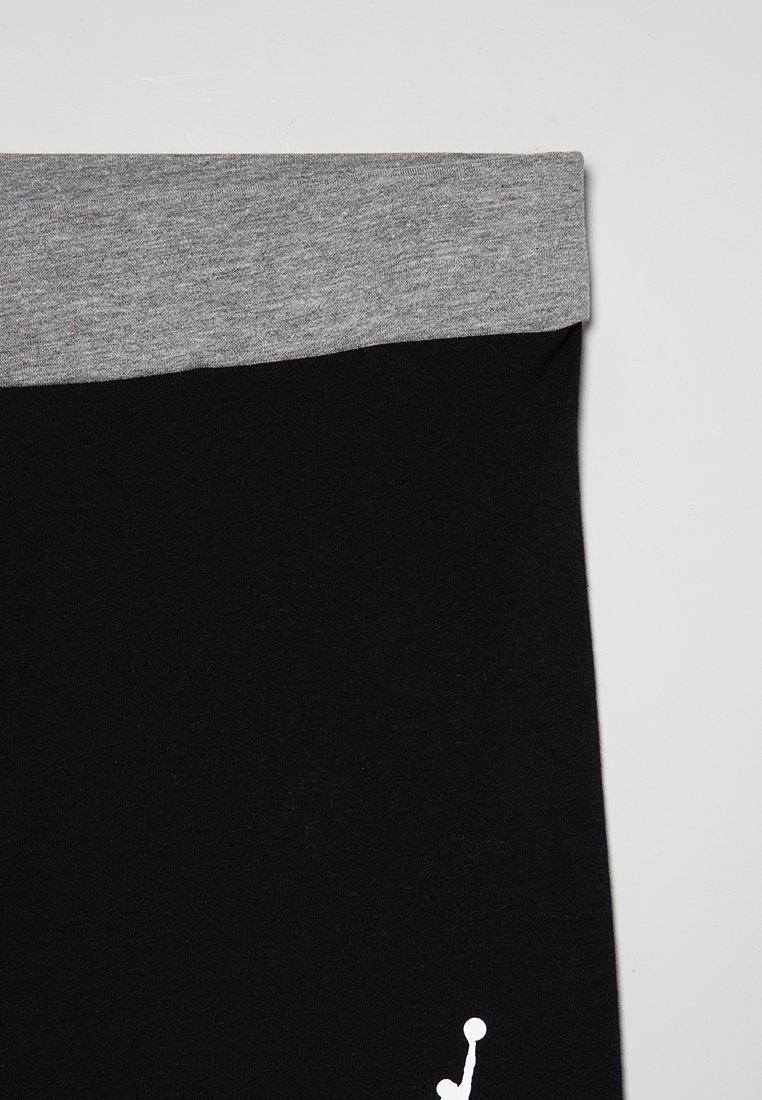 Leggings di cotone neri con un elastico grigio in vita, caratterizzati da un logo bianco in basso a destra. Texture liscia e design aderente.