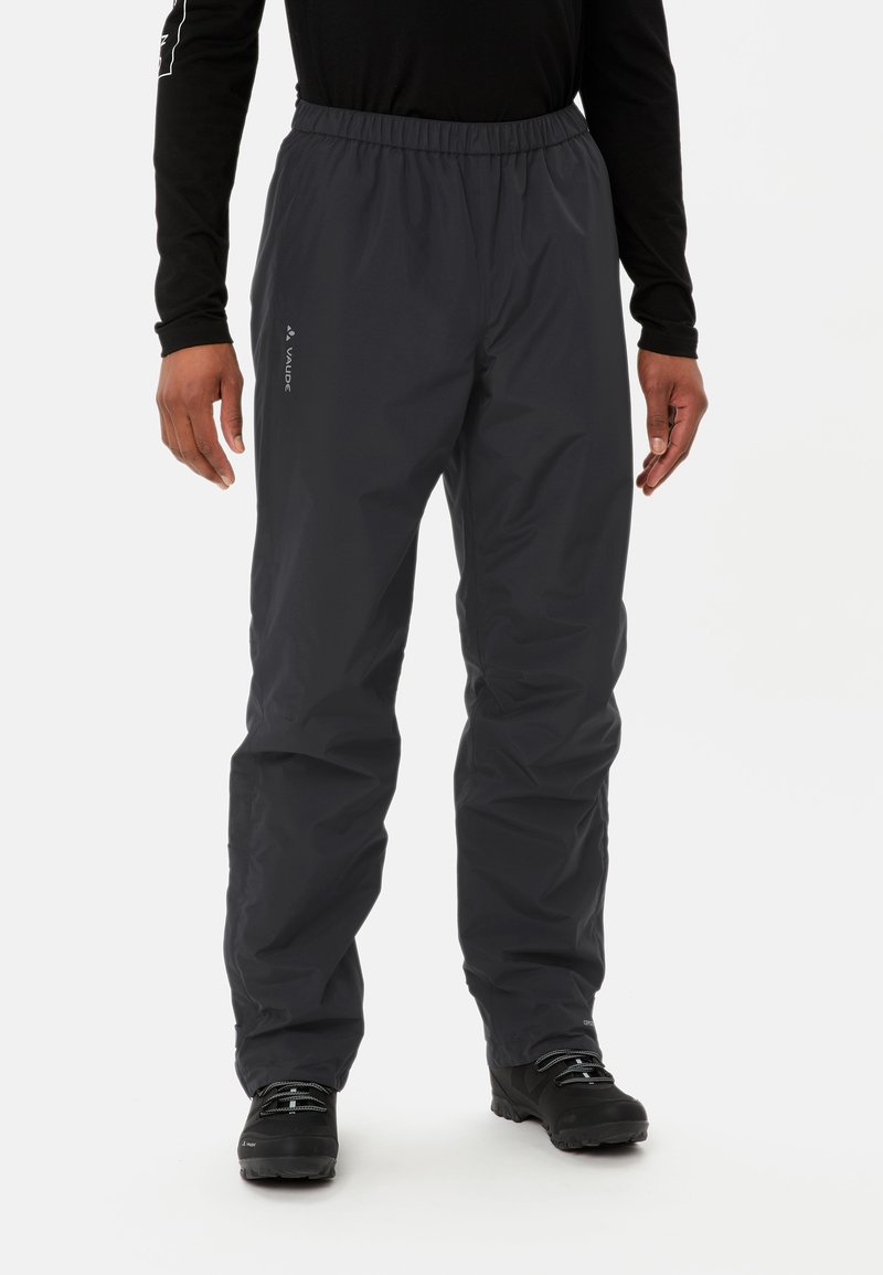 Pantalons gris imperméables avec une taille élastique, des jambes fuselées et un branding subtil. Associés à des bottes de plein air noires, ils présentent une texture lisse.