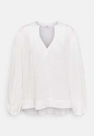 Blusa bianca a maniche lunghe con scollo a V, caratterizzata da morbide pieghe e polsini arricciati, realizzata in un tessuto leggero e testurizzato.