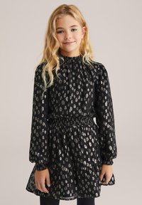 Crna haljina s srebrnim uzorkom leoparda, smuđeni struk, dugi rukavi i volanasti rub. Tkanina izgleda lagano i blago prozirno.