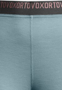 Light blue fabric with a smooth texture, featuring a black waistband with pink lettering. The design is fitted with visible seams.