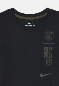 Črna majica s kratkimi rokavi Nike s krožnim izrezom in logotipom Paris Saint-Germain ter napisom "Zasnovano po natančnih specifikacijah prvakov" na prsih.