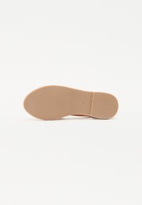 Flat såle i lys beige gummi med en svakt teksturert overflate og rund tå. Ingen synlige merkinger eller mønstre.