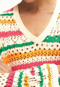 Strickpullover mit V-Ausschnitt in Creme, mit gestreiften Mustern in Rosa, Grün, Orange und Gelb. Durchgehend offene Struktur.