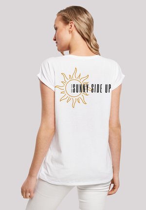 White short-sleeve t-shirt featuring a large yellow sun graphic with text "KEEP YOUR SUNNY SIDE UP" on the back. Soft fabric, relaxed fit.