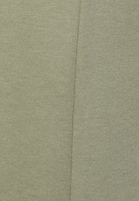 Light green fabric with a textured surface, featuring a subtle sheen. The design shows a seam running vertically through the material.