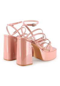 Sandalias de plataforma de charol rosa con múltiples correas delgadas y hebillas ajustables en el tobillo, con un diseño de tacón grueso.