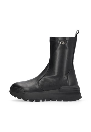 Botte mi-mollet en cuir noir avec semelle épaisse et rainurée, bout arrondi, languette de tirage et emblème logo argenté près du haut.
