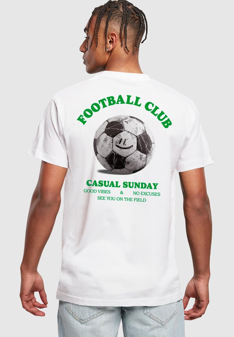 Camiseta de algodón blanca con un gráfico en blanco y negro de un balón de fútbol. Texto en verde: "CLUB DE FÚTBOL", "DOMINGO CASUAL" y más.