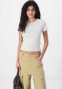 Tricou patruns cu mânecă scurtă de culoare gri deschis, cu decolteu rotund, asortat cu pantaloni cargo bej, având buzunare laterale.