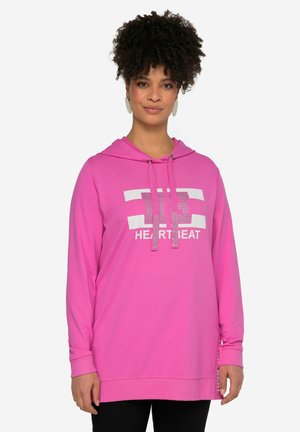 Sudadera rosa con mangas largas, capucha ajustable con cordón y texto "HEARTBEAT" en blanco. Presenta aberturas laterales y una textura de tela suave.