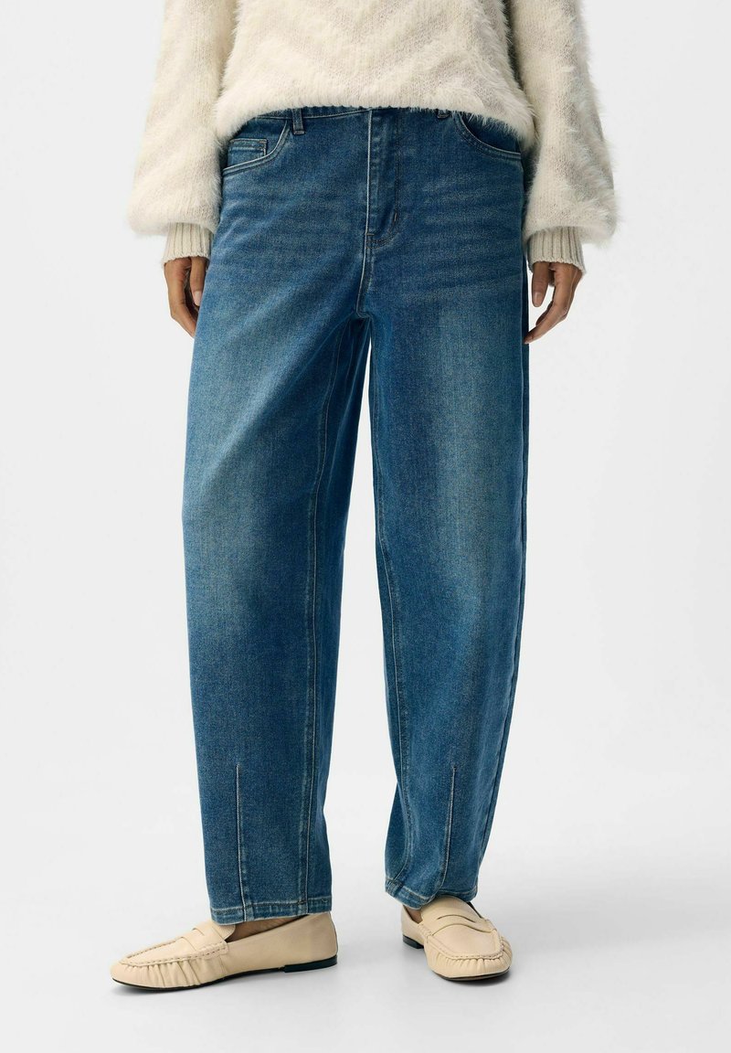 Ljusblå, högmidjade denimjeans med en lös passform, som har framfickor och subtila blekningar. Matchade med beige slip-on mockasiner.