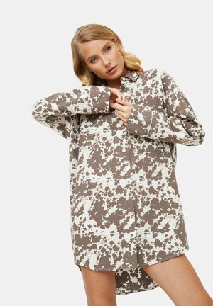 Robe chemise à boutons brune et blanche avec un motif imprimé vache, manches longues et coupe décontractée, dotée d'un col.