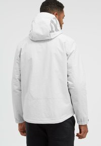 Chaqueta blanca, ligera, hecha de tela suave y con capucha. Presenta puños elásticos y un diseño simple sin logotipos o patrones visibles.
