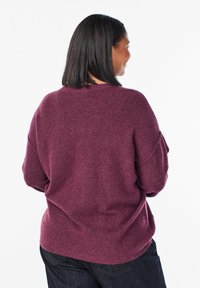 Bordo pleteni pulover s opuštenim krojem, okruglim izrezom i spuštenim ramenima, s mekim tkivom i rebrastim detaljem na rubu.