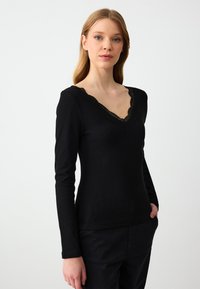 Schwarzes Langarm-Oberteil mit geripptem Struktur und tiefem V-Ausschnitt, verziert mit Spitzenbesatz. Figurbetontes Design mit glatter Oberfläche und subtilem Stretch.