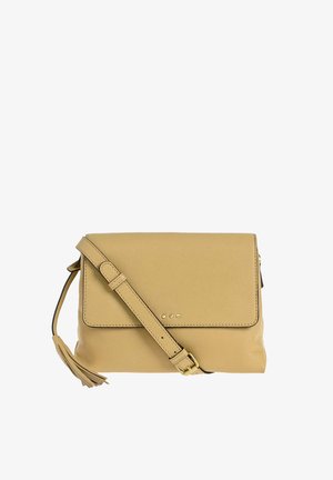 Sac bandoulière en cuir beige avec une sangle ajustable, une fermeture à rabat, de petites clous métalliques sur le devant et un détail de pompon sur le côté.