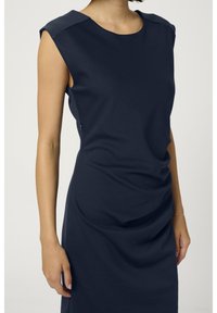 Robe bleu marine en tissu lisse, avec un col rond, des manches courtes et des détails froncés à l'avant.