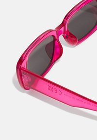 Fuchsia sunglasses with dark lenses, rectangular shape, and glossy plastic frame. Features branding and compliance details on the temple.