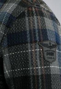 Flanellen shirt met een multikleurig ruitpatroon in grijs, blauw en bruin. Inclusief een zwarte patch met logo en tekst op de schouder.