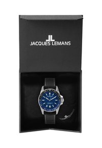 Reloj analógico azul con acentos plateados y correa de cuero negra, presentado en una caja negra con logo blanco y forro interior suave.