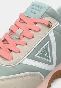 Kergelt roheline ja beez tennisekets, roosa paelaga, valgete aktsentidega ning kolmnurkse logoga. Tekstuuritud materjalid ja kummist tallad.