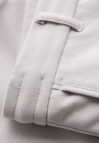 Hellgrauer Stoff, der ein strukturiertes Gewebe zeigt. Verfügt über eine gefaltete Kante und ein kleines Schleifchen-Detail, welches die Dicke und Haltbarkeit des Materials betont.