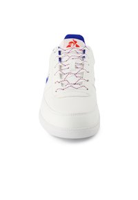 Sneaker bianco con accenti blu, caratterizzato da cuciture strutturate e una superficie liscia. Logo rosso sulla linguetta, con lacci multicolore.