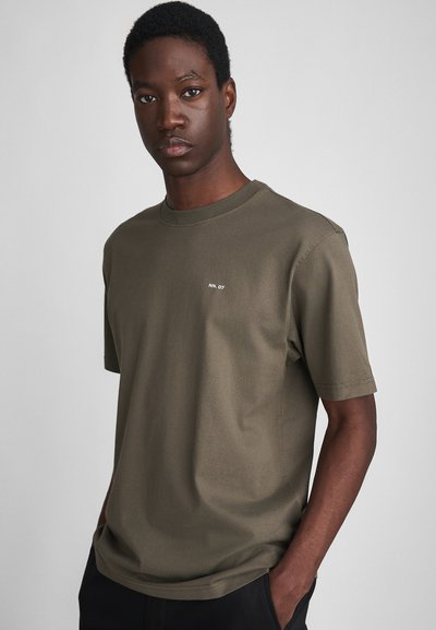 T-shirt en coton vert olive avec un col rond, des manches courtes et un petit logo blanc sur la poitrine gauche. Texture lisse et coupe décontractée.