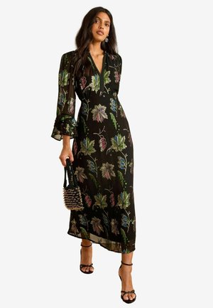 Schwarzes Maxikleid mit floralem Stickerei in Lila, Grün und Blau. Verfügt über lange, geraffte Ärmel und ein V-Ausschnitt-Design, kombiniert mit Riemchenschuhen.